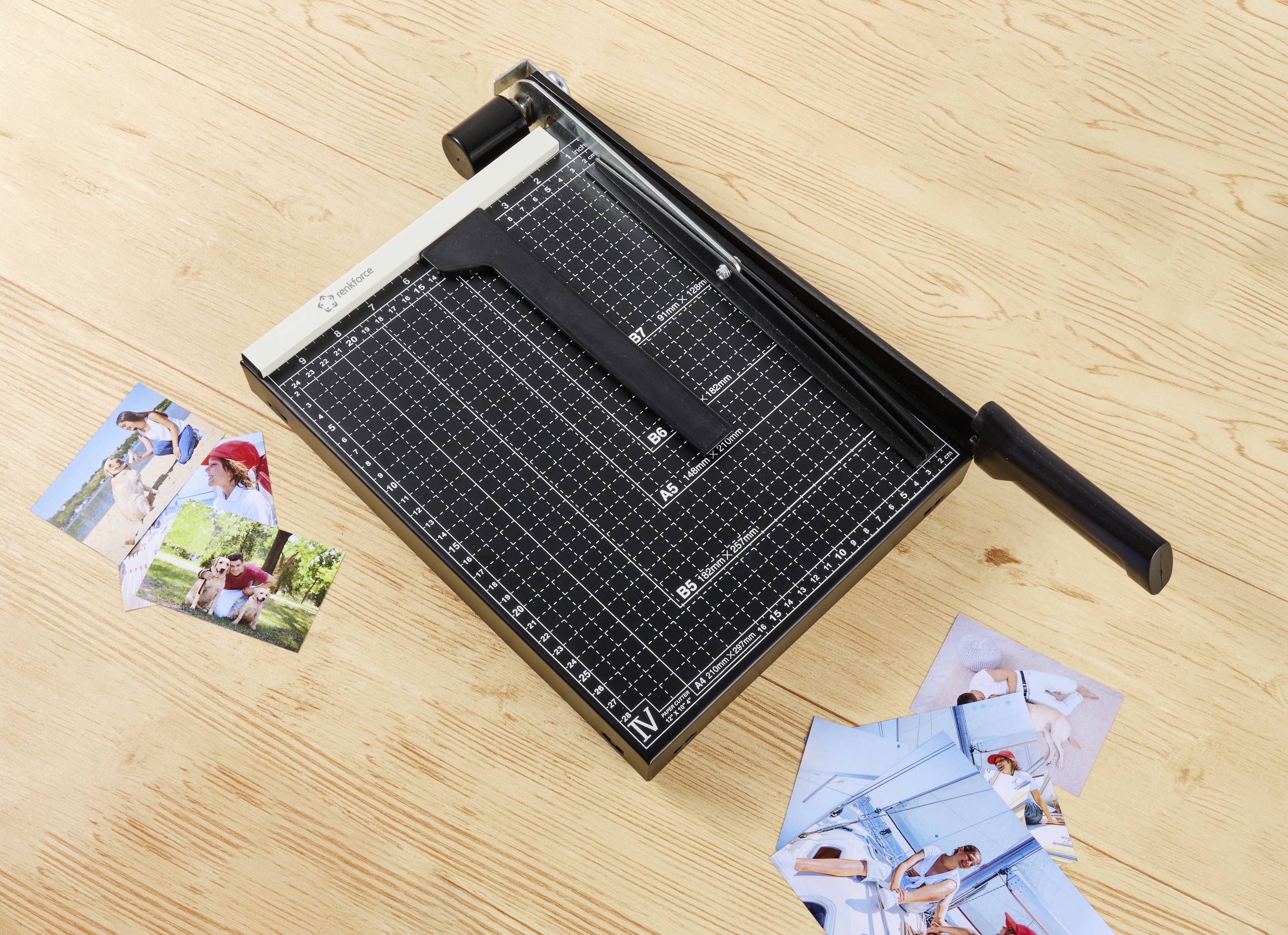 A paper cutter on a wooden table, surrounded by several colourful photographs.