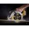 A hand is operating a yellow circular saw cutting through a wooden board. The saw is spinning rapidly, generating sawdust.