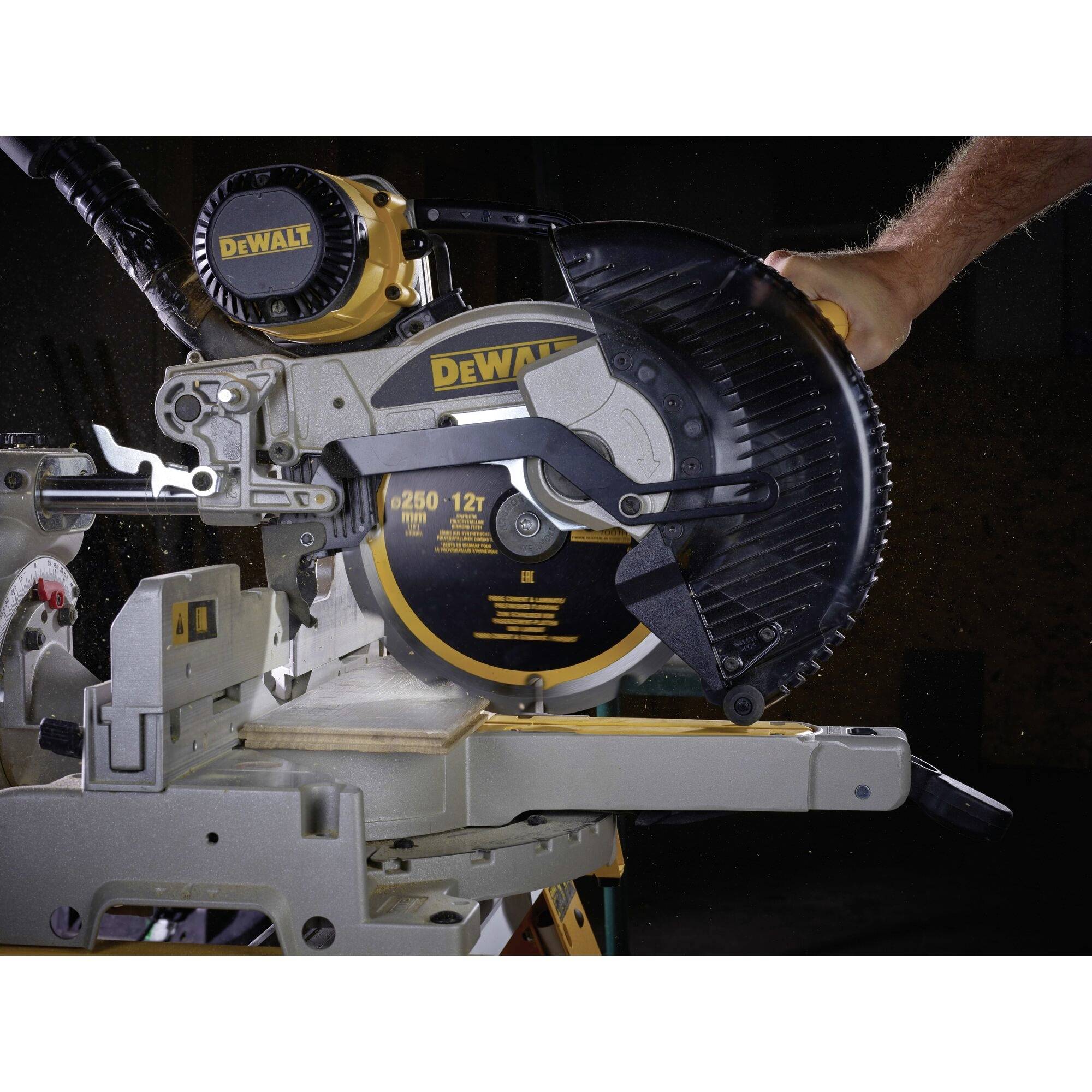 An electric circular saw is being operated by a person. The saw is switched on, and wood chippings are flying during cutting.
