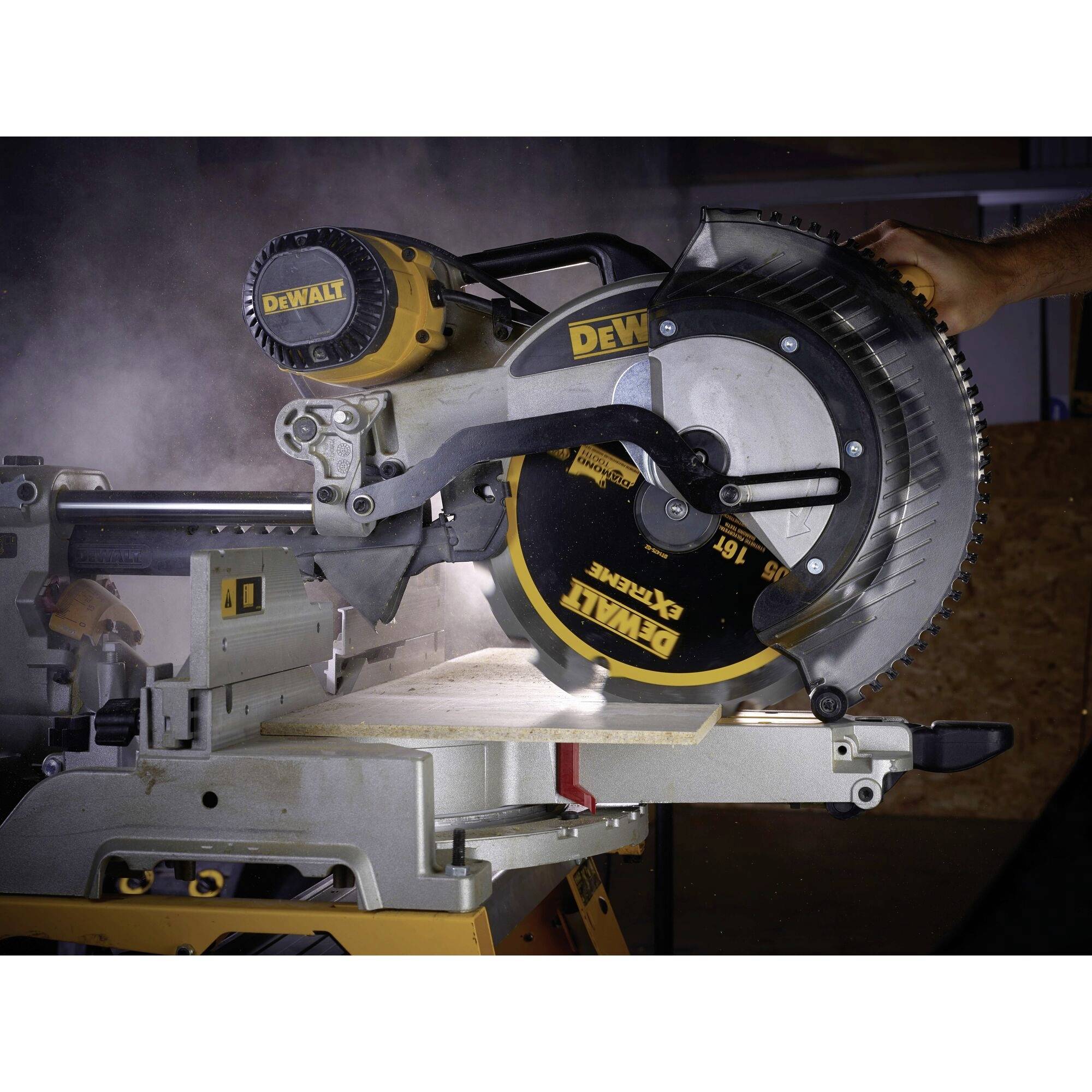 An electric mitre saw cuts wood with precision. Dust rises as a person operates the machine.