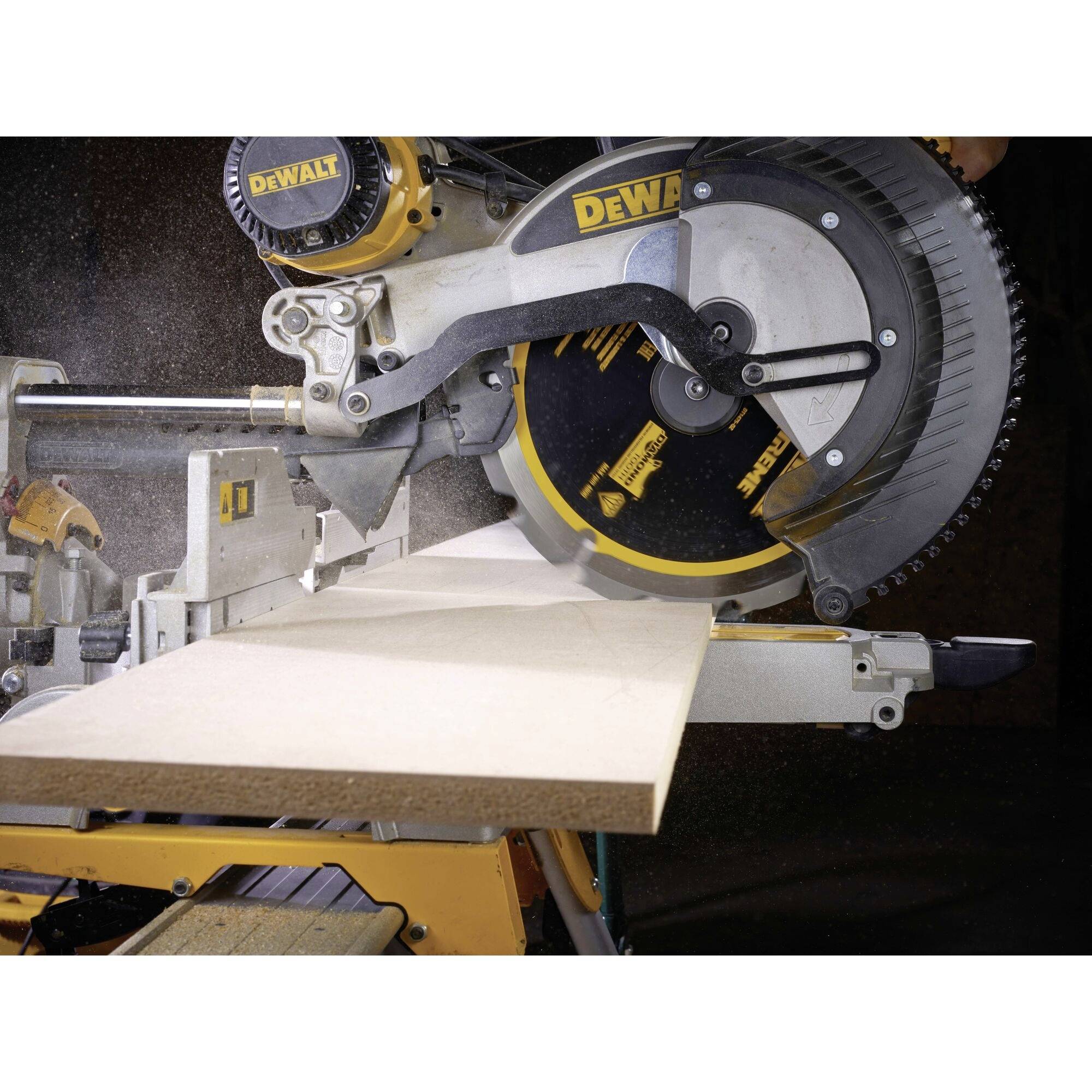 A mitre saw cutting a plank of wood. Wood shavings are visible as the saw blades slice through the board.