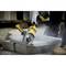 A person is cutting concrete blocks with a yellow angle grinder. Dust is rising.