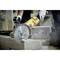 A person is cutting concrete stone blocks with a yellow, electric cutting angle grinder. Dust is being generated in the process. Protective clothing is visible.