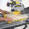 A person is cutting a beige tile with a yellow DeWalt circular saw on a workbench.