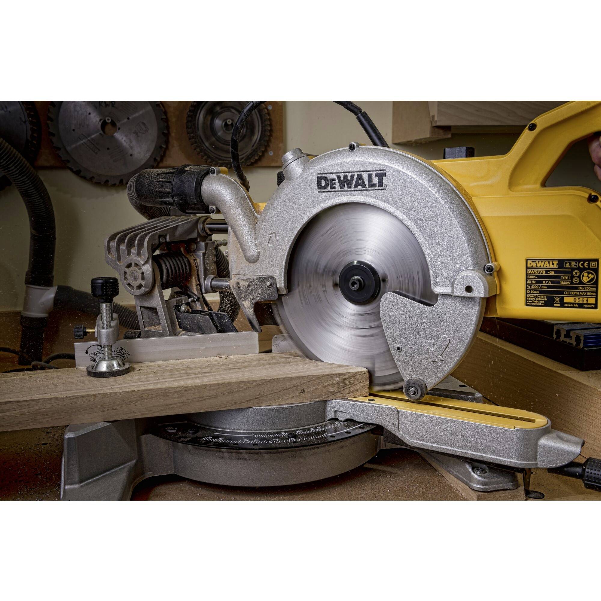An electric mitre saw is cutting a wooden board. The saw is yellow and silver, and the board is being precisely worked on a workbench.