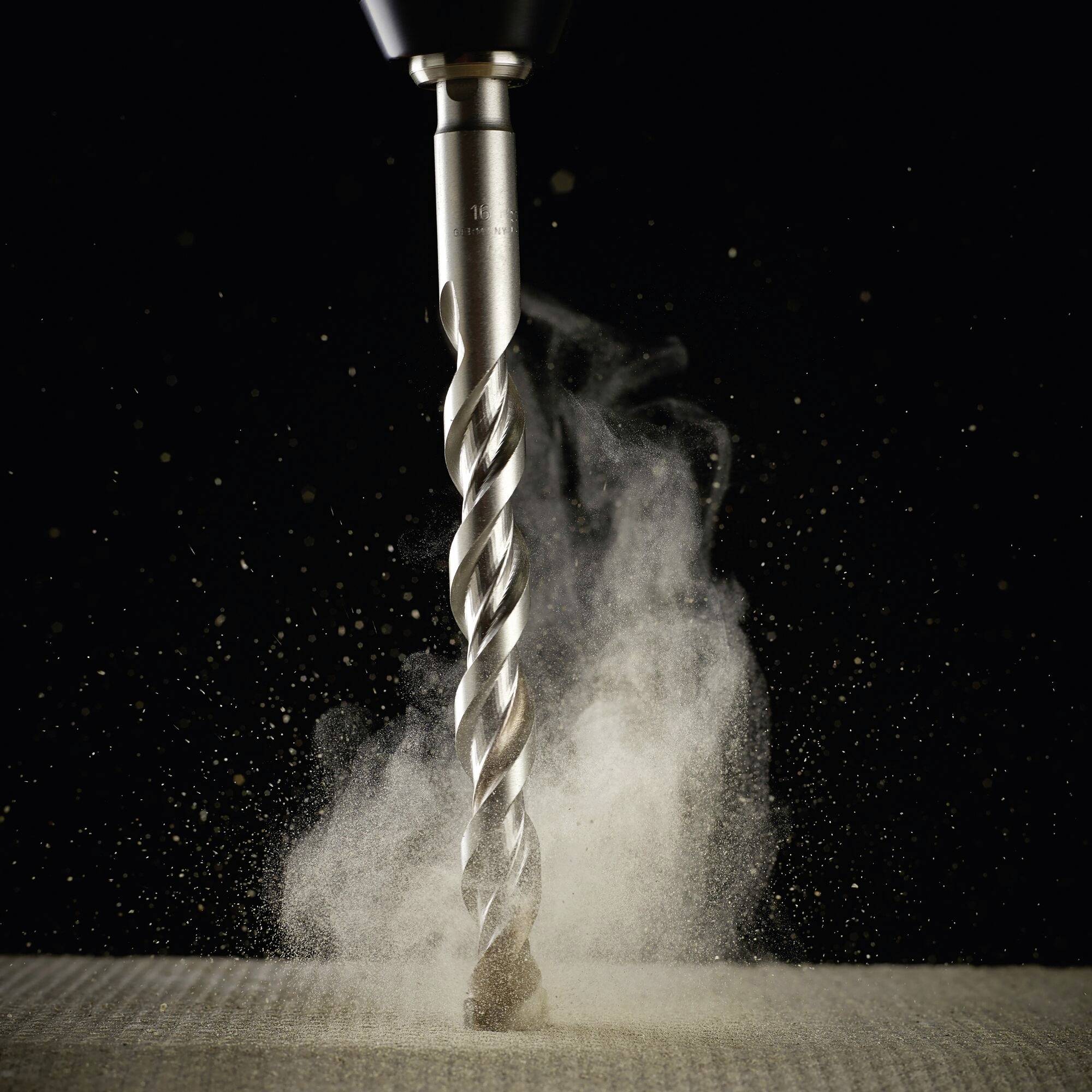 Drill creating a dust cloud on a wooden surface.