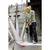 A worker on a building site is wearing protective clothing and using a drill hammer on a concrete block. Scaffolding is visible in the background.