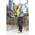 A construction worker in safety gear is drilling holes in concrete with a hammer drill on a large construction site with steel beams in the background.