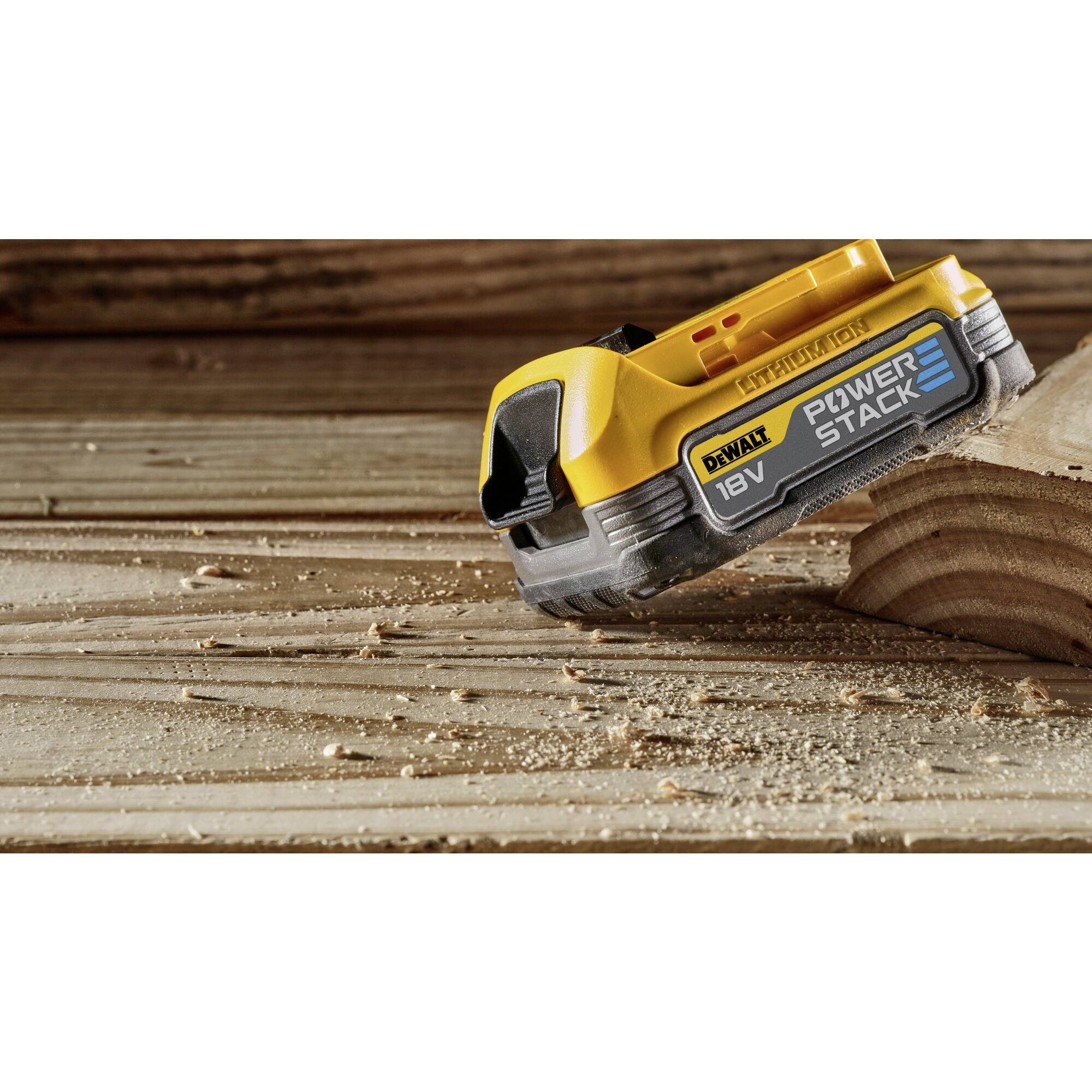 Cordless drill is resting on a wooden surface. In the foreground, a yellow battery with the inscription '18V POWER STACK' is visible.