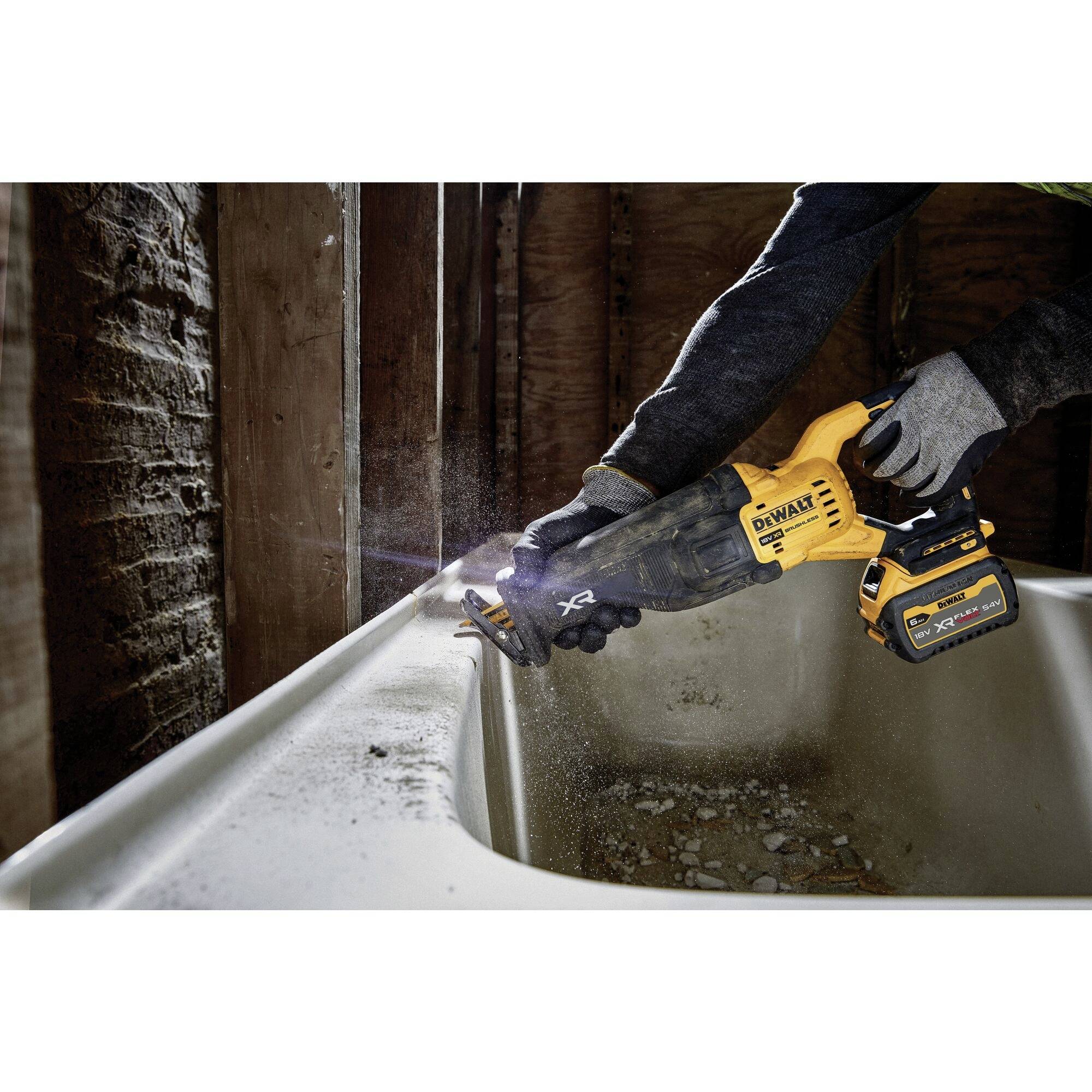 A person is using an electric tool to work on a bath/bathtub in an unfinished building/property.