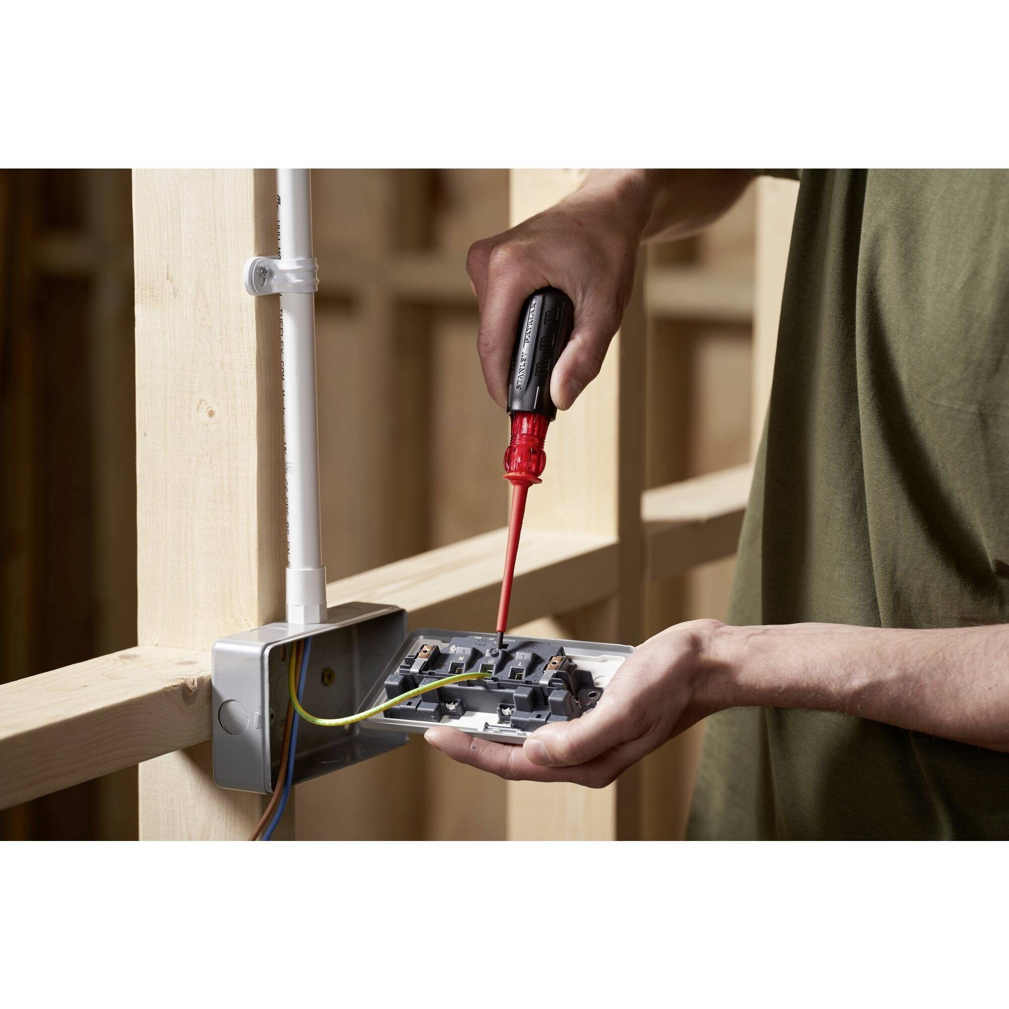 A person installs or repairs a socket by working on the wires with a screwdriver.