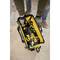 A tradesman in workwear is carrying an open tool bag full of tools, including a yellow cordless drill.