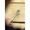 A person is holding a spanner over a wooden table. The background is blurred, with the focus on the tool and the hand.