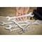 A set of open-ended spanners, some lying on a table; a hand is holding one of the spanners.