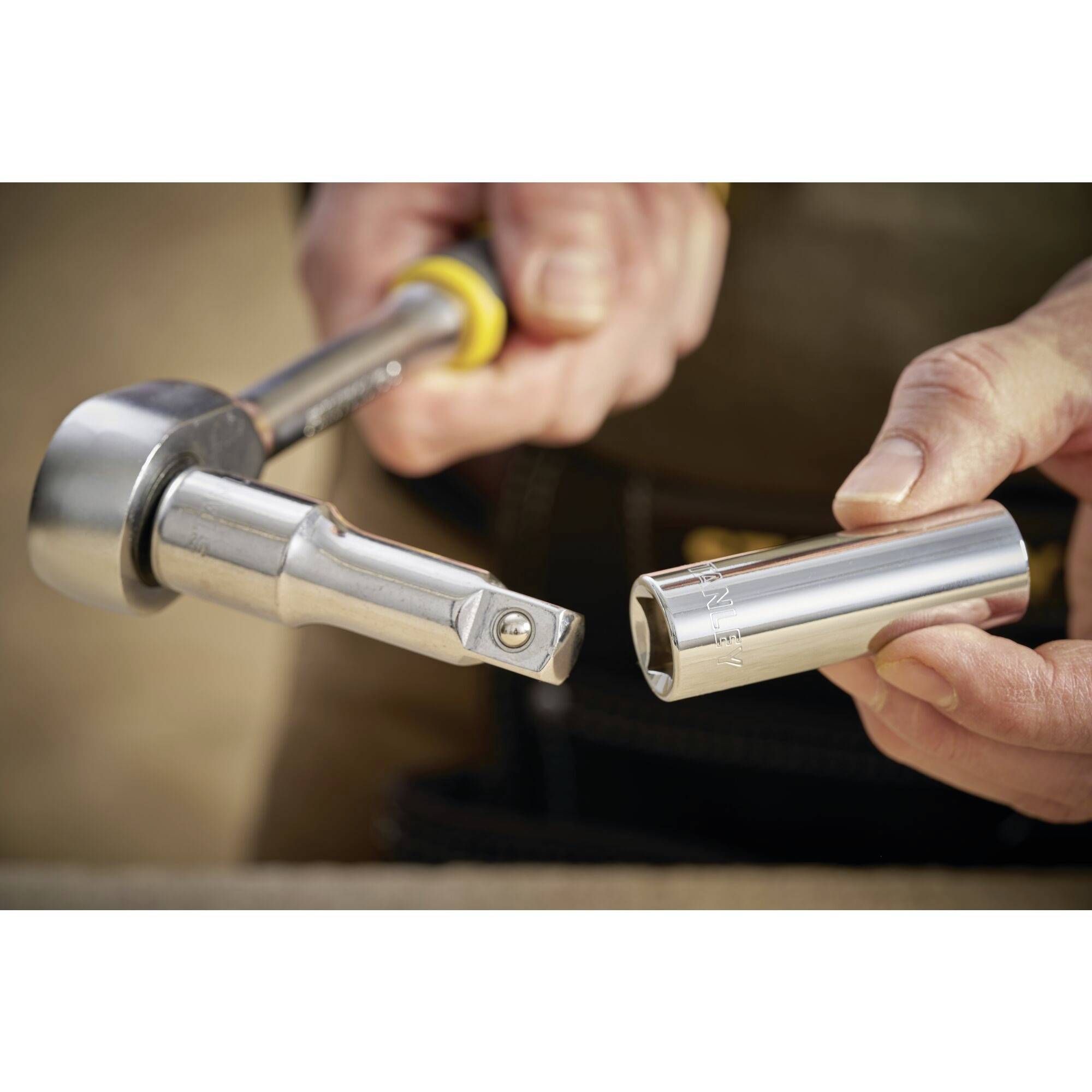 A person is holding a silver socket wrench set, ready for use. The focus is on the gleaming tool components.