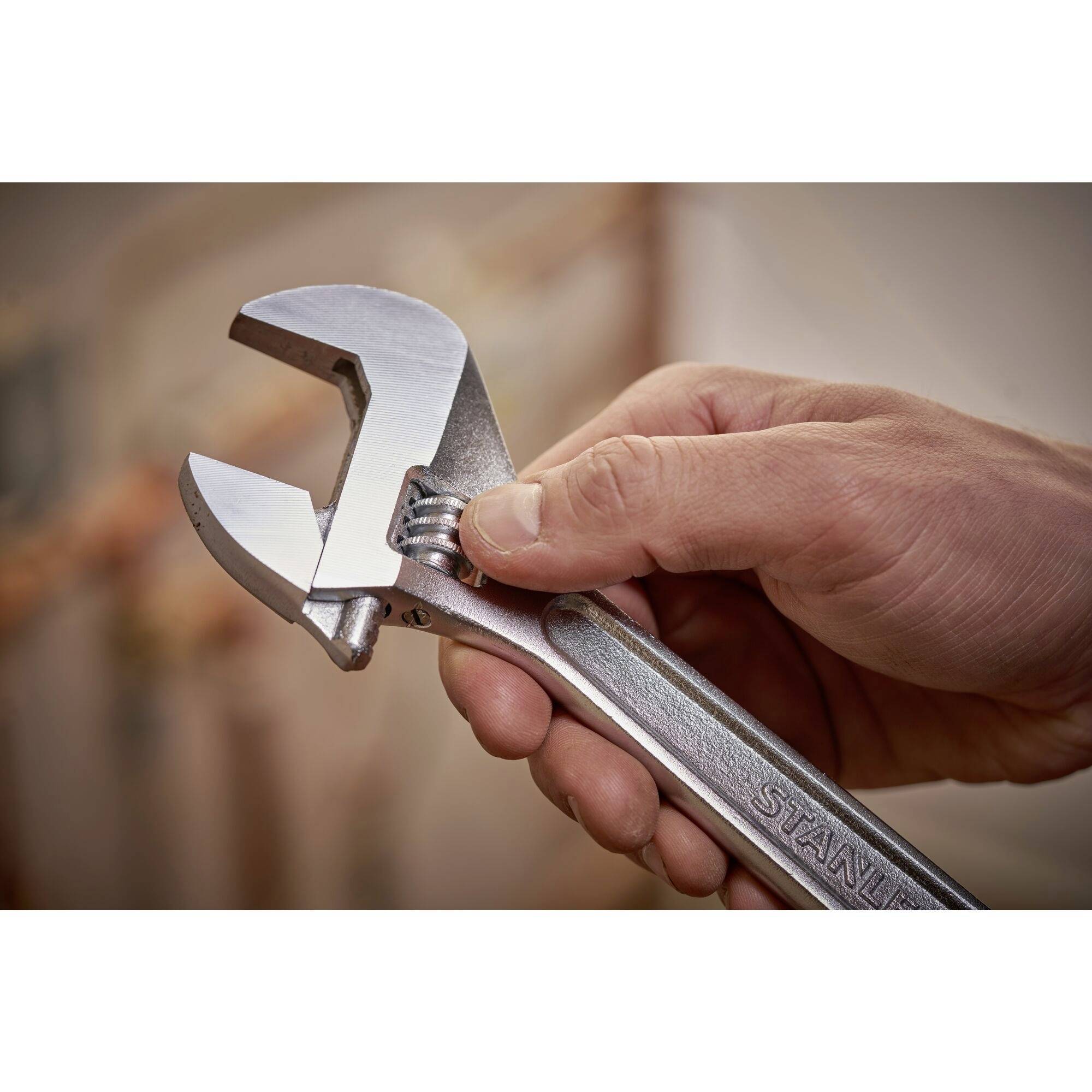 A hand holds an adjustable spanner against a blurred background, ready to adjust hardware.