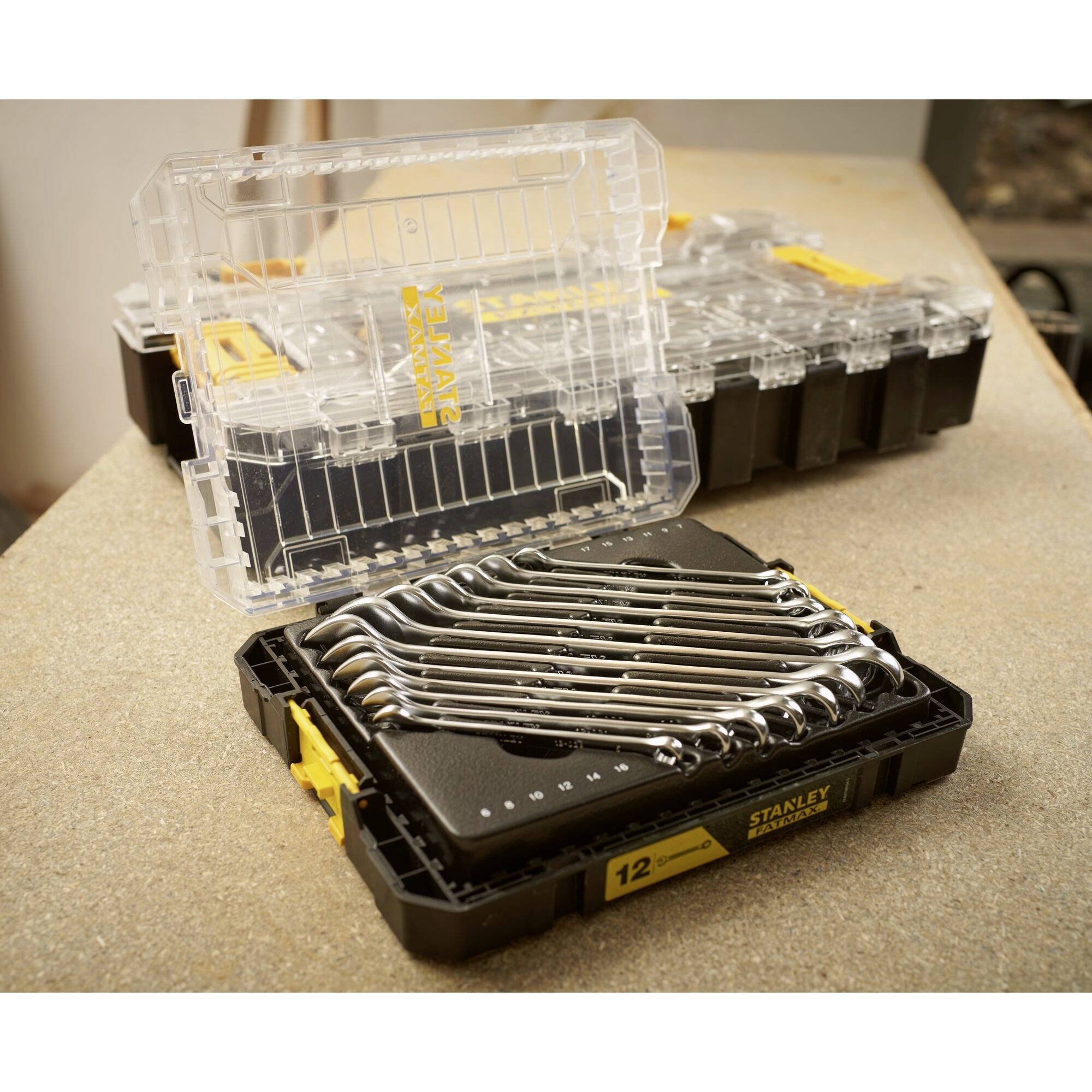 'Set of ring spanners in an open toolbox on a workbench. Another closed toolbox in the background.'