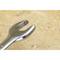 A silver adjustable spanner lies on a wooden table. The tool is slightly worn and suitable for repair work.