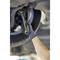 A hand in a glove uses a spanner to loosen a bolt on a car tyre.