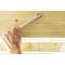 A hand is holding a spanner working on a wooden surface.