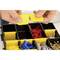 Close-up of hands opening the yellow dividers of a storage box. Colourful wall plugs and screws are neatly organised inside.