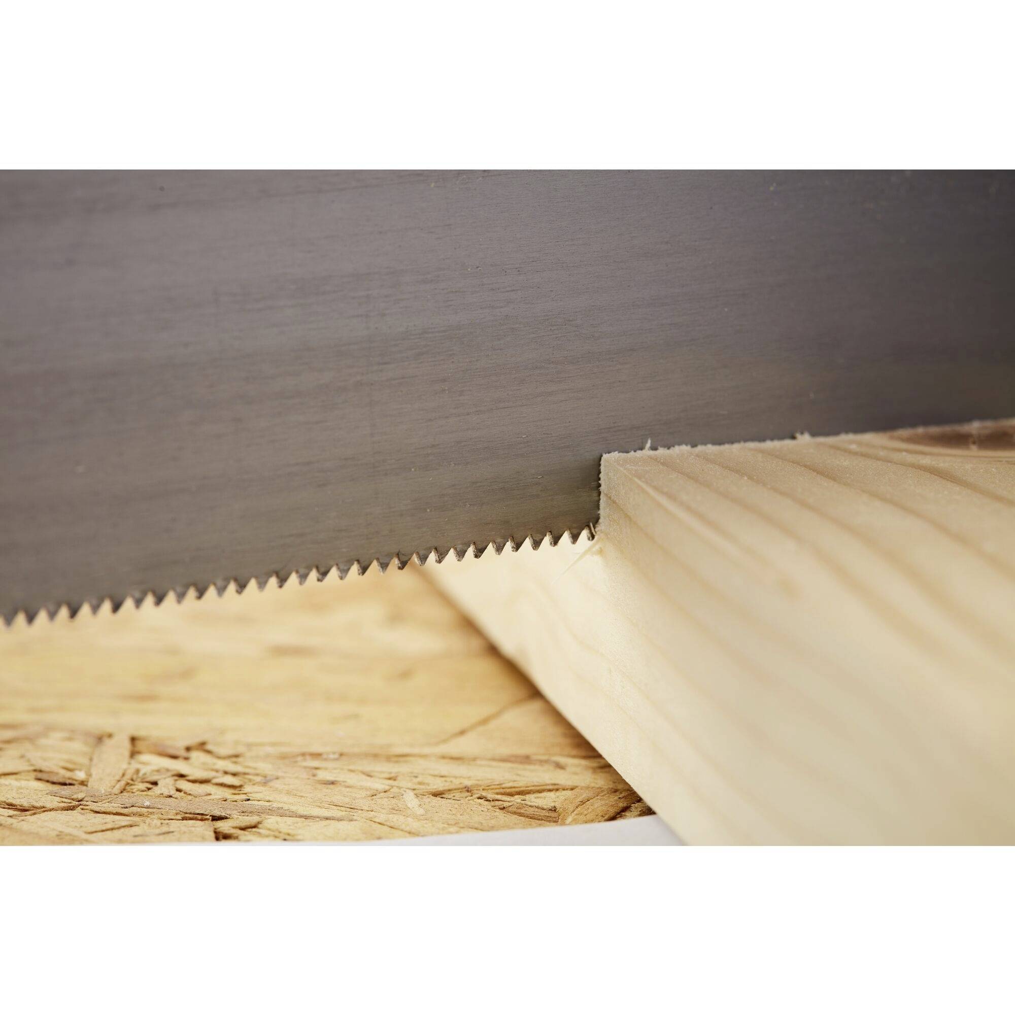 A handsaw blade cuts precisely through a piece of light-coloured wood lying on a workbench.