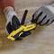 A person wearing gloves is operating a yellow Stanley tool on a wooden surface.