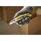 A gloved hand is holding a yellow utility knife with grey details. Blurry cardboard boxes can be seen in the background.