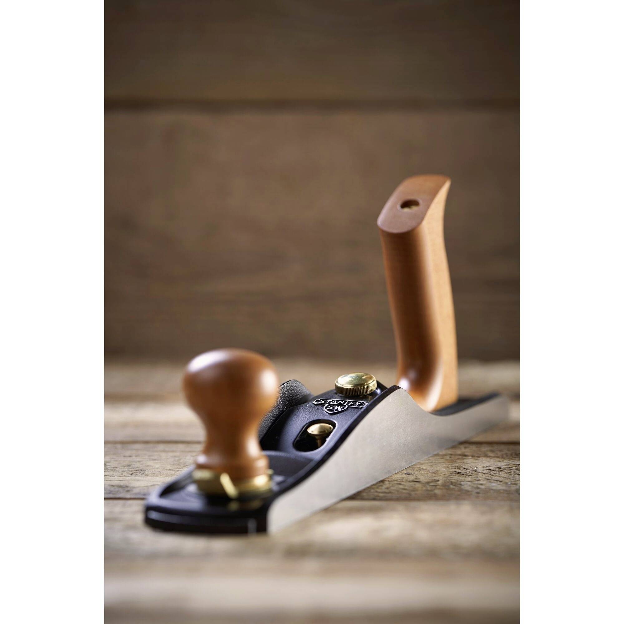 Plane tool on a wooden surface, with a wooden handle. Ideal for smoothing and shaping wood.