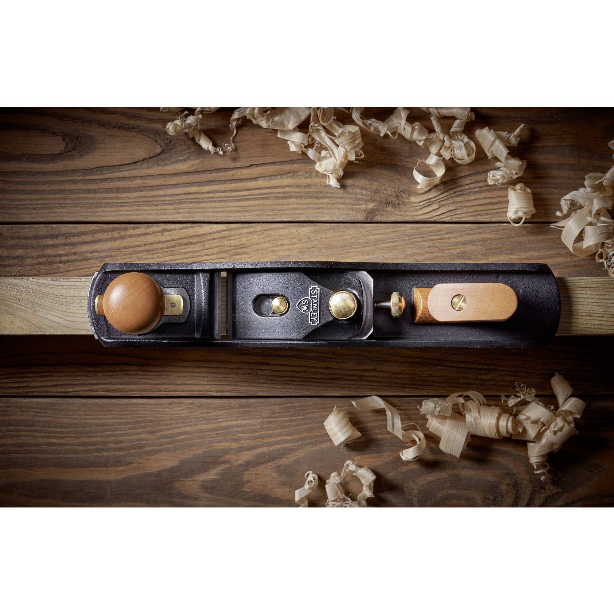 Plane on a wooden table with wood shavings, demonstrating traditional carpenter's tool and its usage.