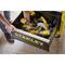 A person opens a drawer containing several yellow Stanley power tools, including a drill and a circular saw.
