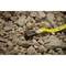 A measuring tape is lying on a floor of coarse gravel. The measuring tape shows a length resting on the stones.