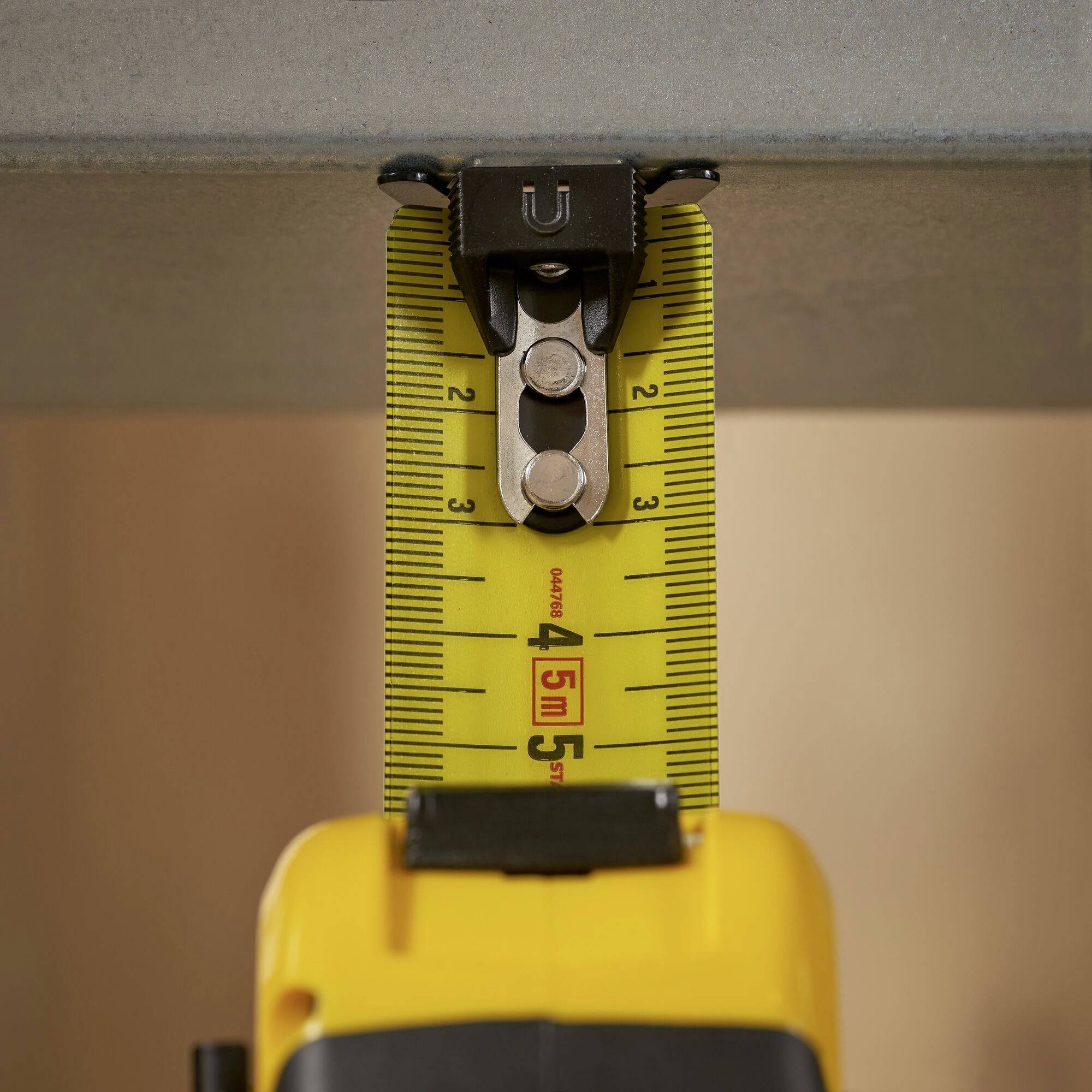A yellow tape measure is used to measure the height of an object that may be part of a construction project.