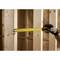 'A person wearing a glove is holding a tape measure against a wooden structure, measuring the distance between two vertical wooden slats.'