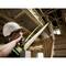 A person wearing a hard hat is measuring the length of a beam in a partially constructed building.