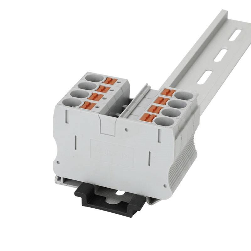 A grey electrical terminal block with multiple slots, mounted on a DIN rail, for wiring in electrical cabinets.
