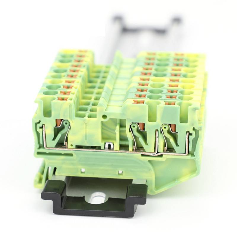 Plastic clip with green and yellow details and multiple connection points, set against a white background. Primary purpose: electrical connections.