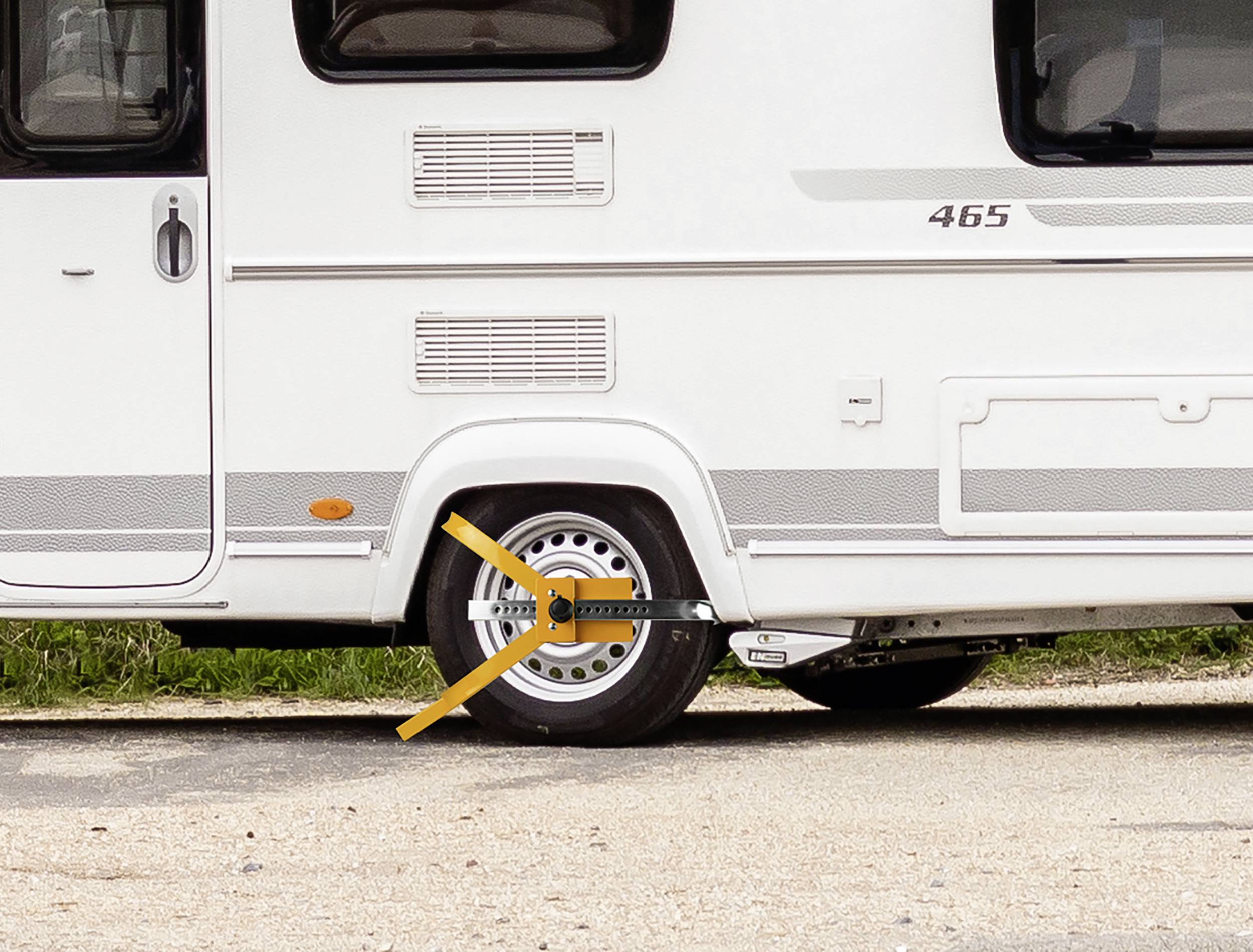 Caravan with a wheel clamp on the right rear wheel parked on asphalt.