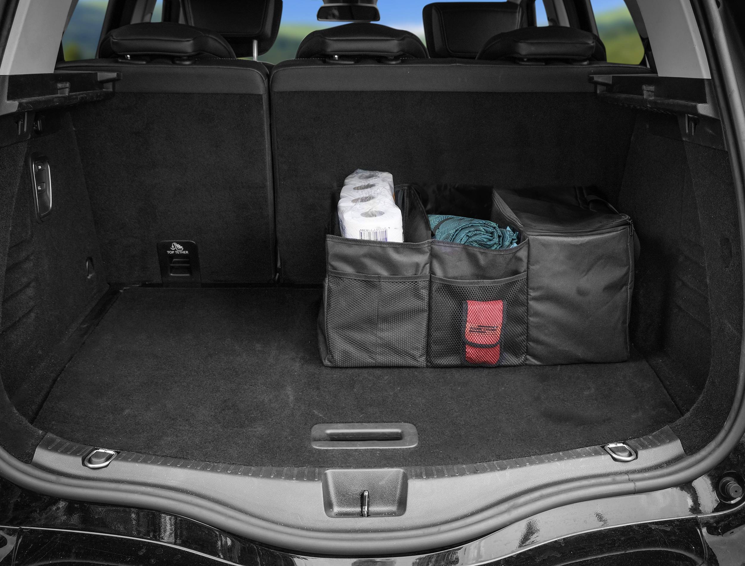 The boot of a car with two storage bags. One bag contains toilet roll, the other a folded item of clothing.