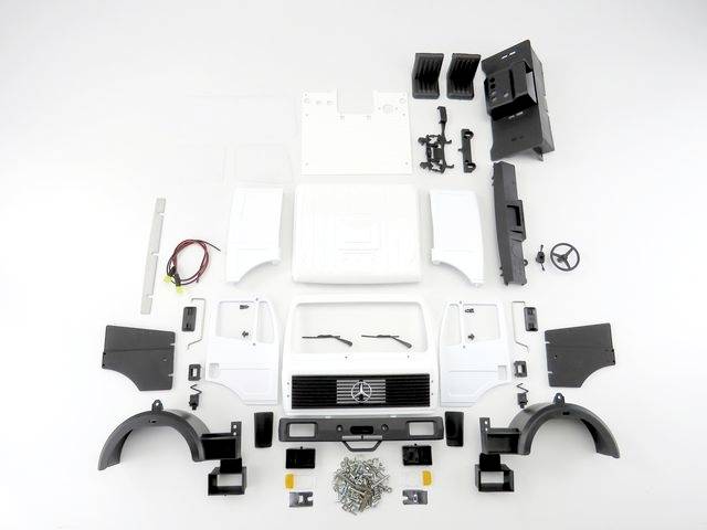 Several components of a model car, including body parts, wheels, a steering wheel and screws, arranged on a white background.