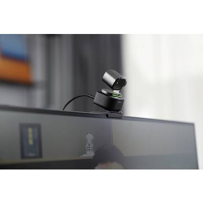 A webcam is mounted on a monitor and is angled slightly downwards. A blurry room can be seen in the background.
