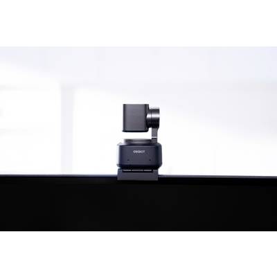 A small, swivelling camera sits on a screen. The camera is mounted on a stable base and is photographing in a bright room.