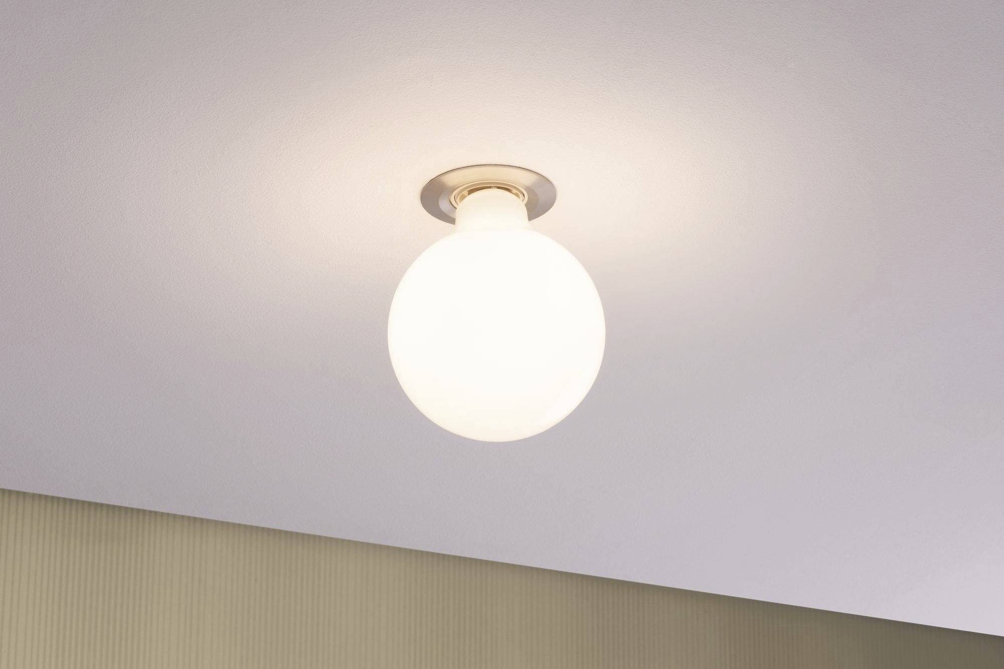A lit light bulb on the ceiling radiates warm light.