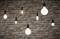 Several hanging light bulbs in front of a brick wall, in different shapes and brightness, create a cosy atmosphere.