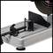 A silver metal clamp on a workbench, with a heavy black cutting wheel situated top right. Workshop environment.