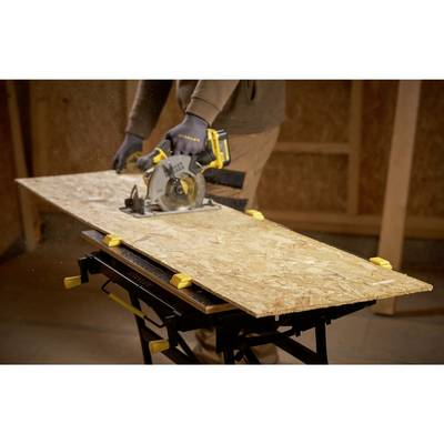 A person is sawing a wooden board with a circular saw on a stand in a workshop.