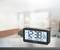 A digital clock shows the time 12:38 PM, with the date 28/12, month 12, and day of the week Saturday. It is sitting on a table in a room.