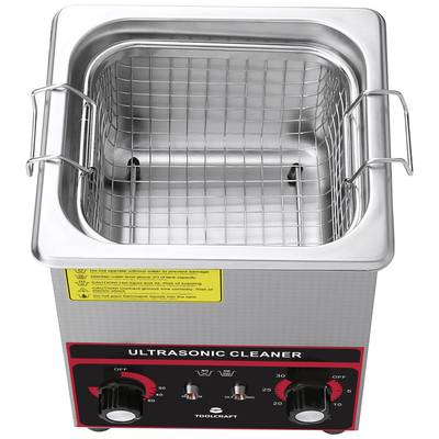 Ultrasonic cleaner with metal basket and control elements in a silver enclosure.