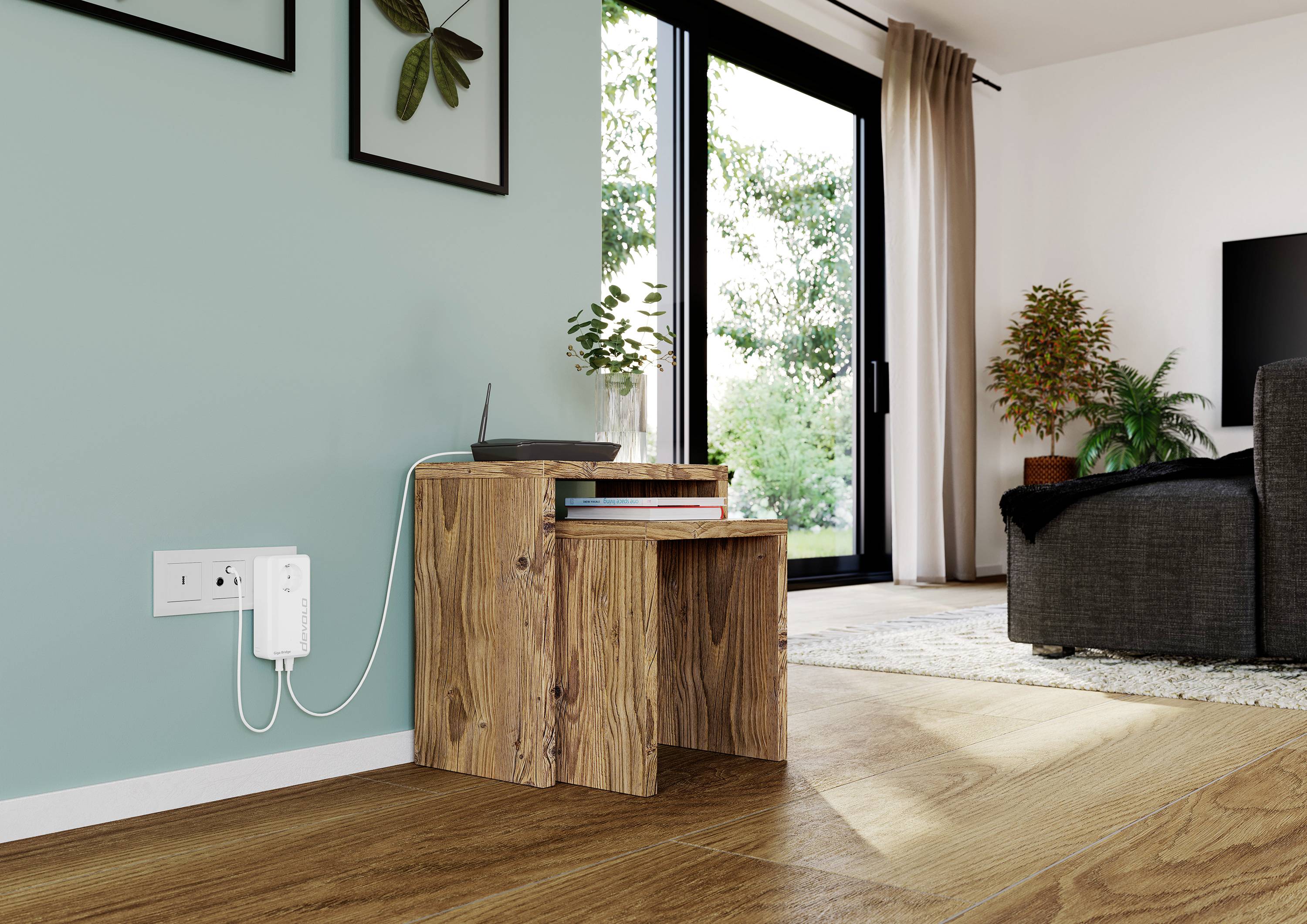 Wooden table with router, plugged into a socket. Green wall with pictures to the left, glass door with garden view to the right. Living room setting.