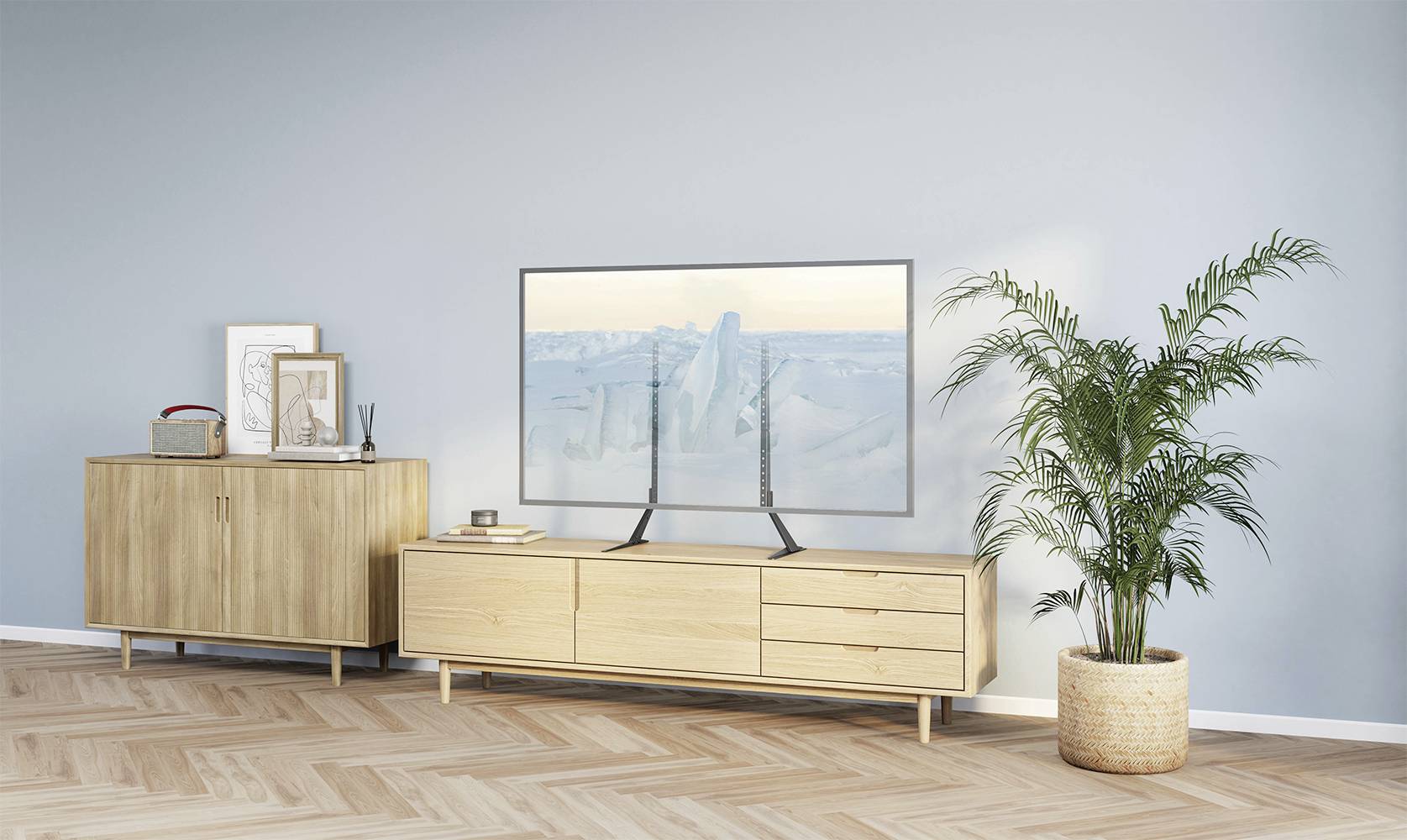 A living room with a television on a low wooden cabinet, surrounded by plants and decorations. Light wooden flooring.